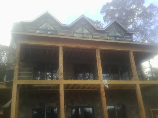 Dormers and porch framing on a large log home under construction — Roof Coating work by our crew in Creighton