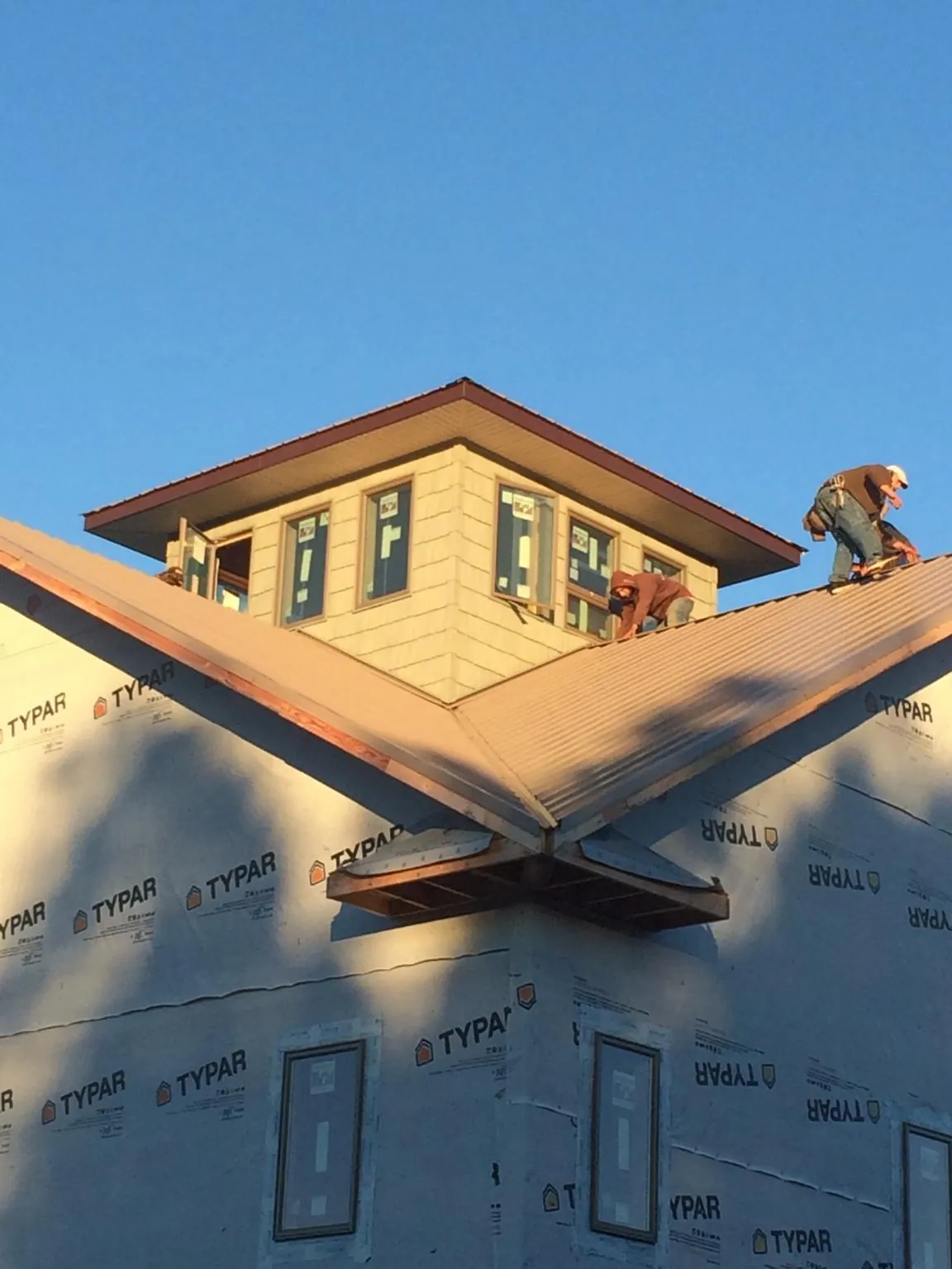 Roofers working around a rooftop cupola on a new metal roof at sunset — Roof Waterproofing in Creighton by Roofing Brothers